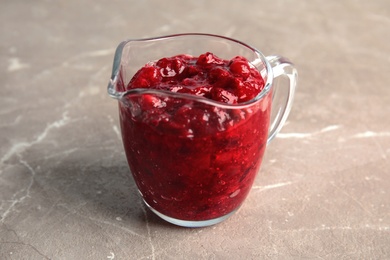 Photo of Tasty cranberry sauce in glass pitcher on table