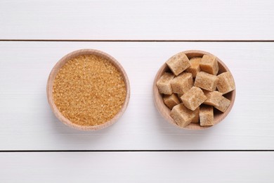 Different types of brown sugar in bowls on white wooden table, flat lay