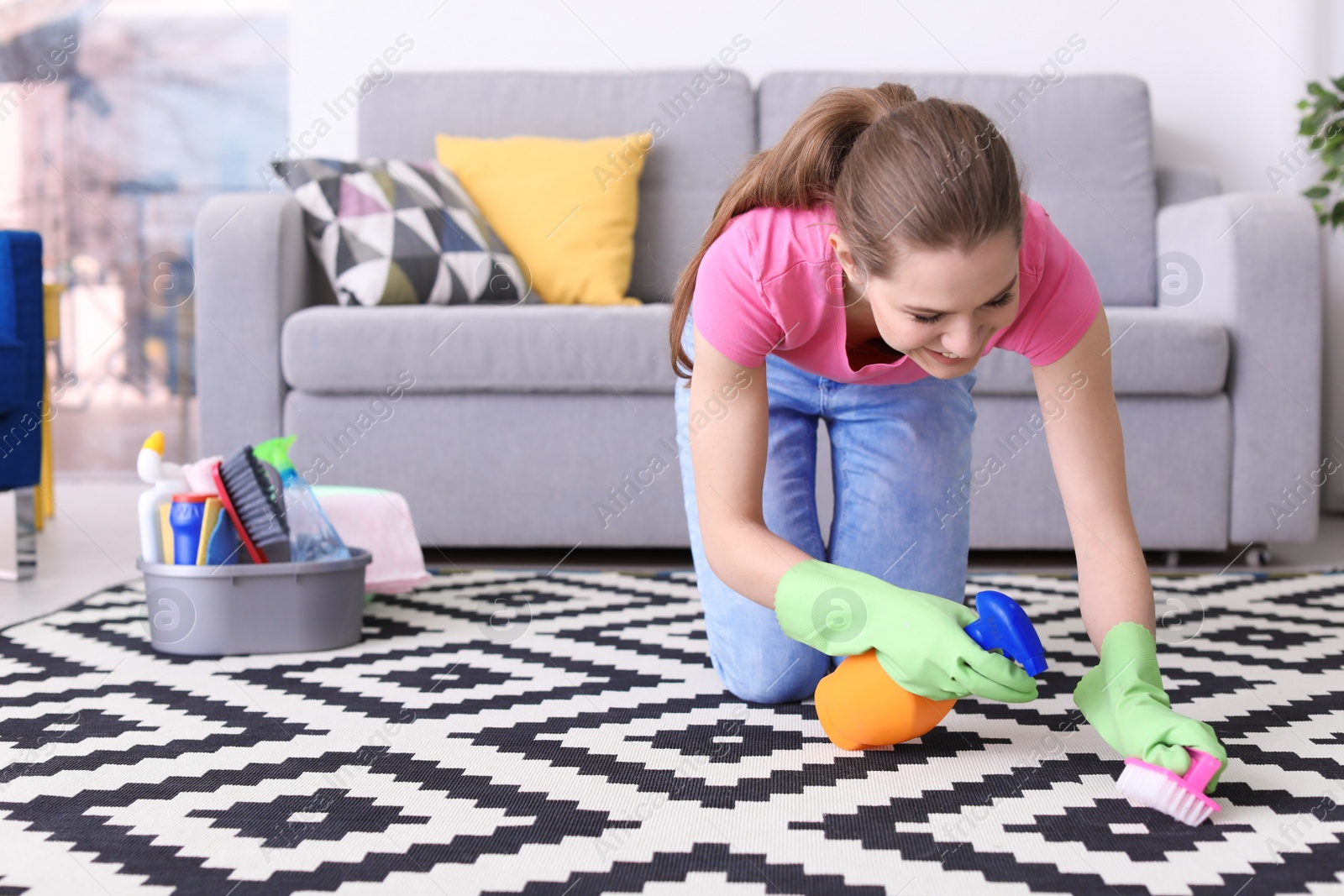 Photo of Woman cleaning carpet in living room