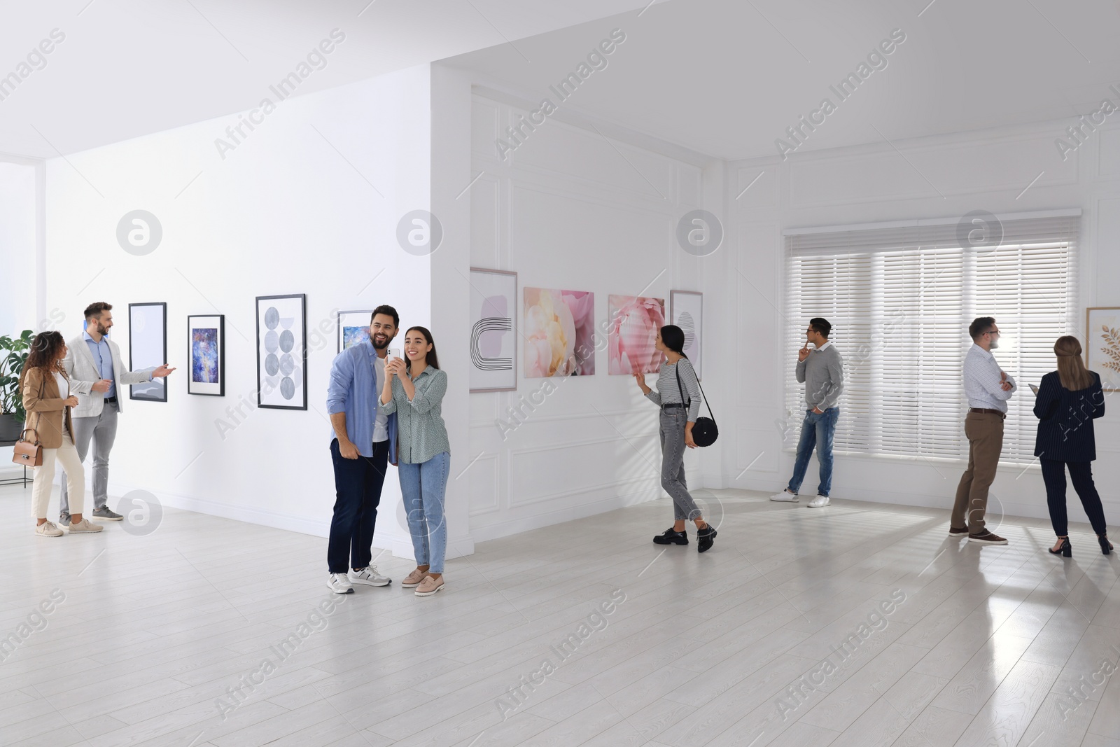 Photo of People viewing exposition in modern art gallery