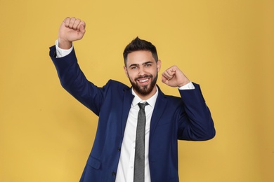 Photo of Happy young businessman celebrating victory on color background