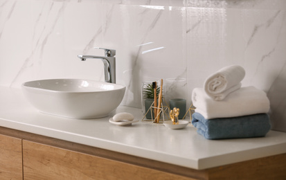 Toiletries and stylish vessel sink on light countertop in modern bathroom