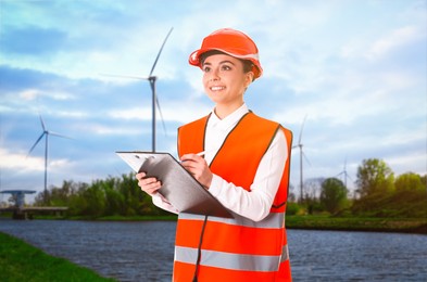 Industrial engineer in uniform and view of riverside and wind energy turbines on sunny day