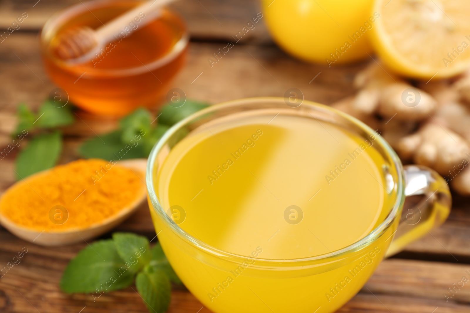 Photo of Immunity boosting drink and ingredients on wooden table, closeup