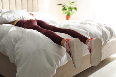 Photo of Lazy young woman sleeping on bed instead of morning training, focus on legs