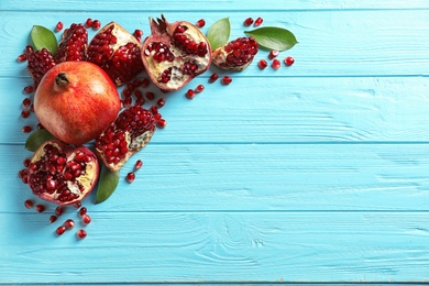 Photo of Composition with ripe pomegranates and space for text on wooden background, flat lay