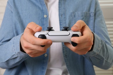 Photo of Man using wireless game controller indoors, closeup