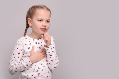 Photo of Girl suffering from sore throat on light grey background. Space for text