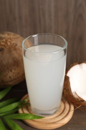 Photo of Glass of coconut water, leaf and nuts on wooden table