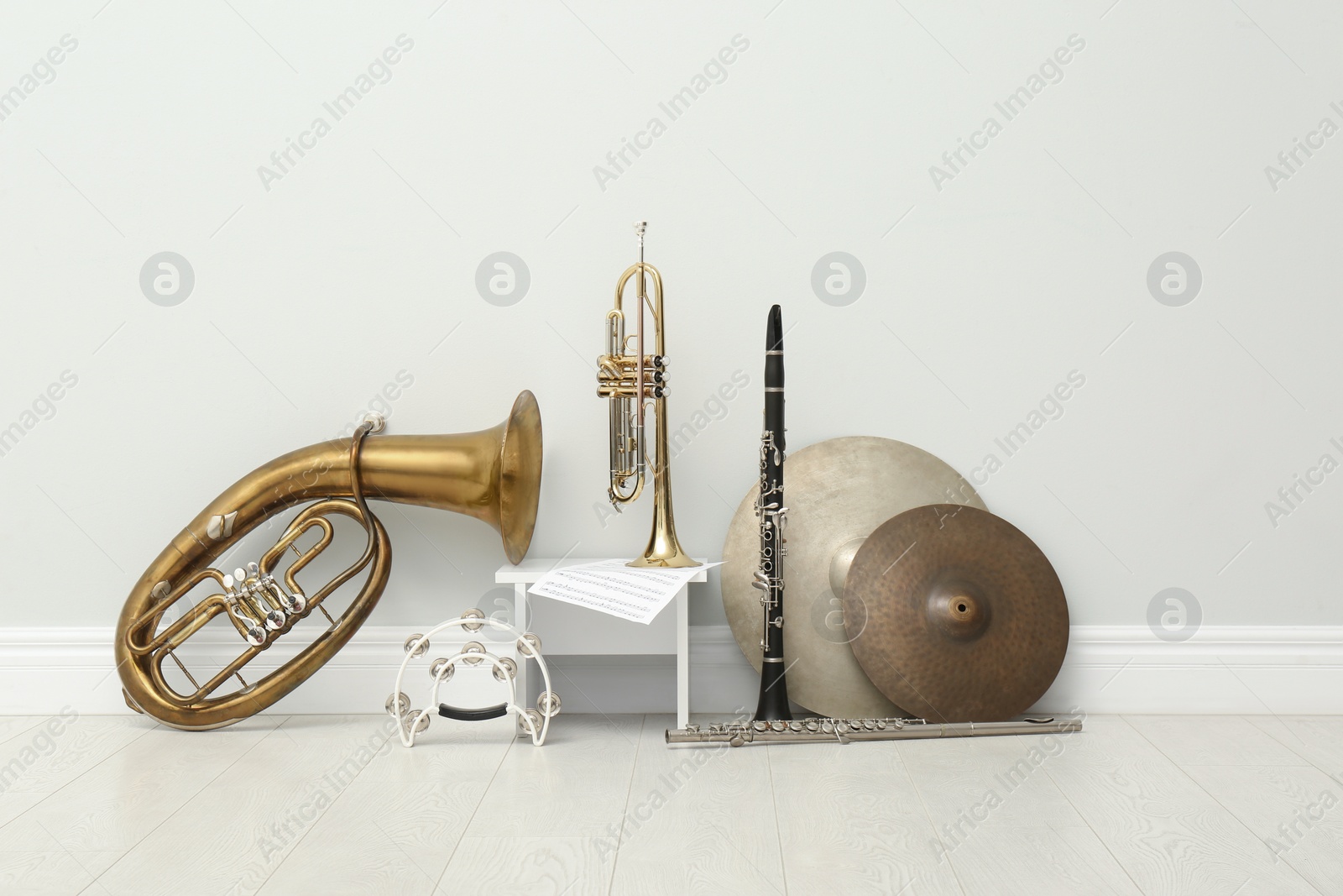 Photo of Different percussion and wind musical instruments near white wall indoors