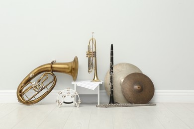 Photo of Different percussion and wind musical instruments near white wall indoors