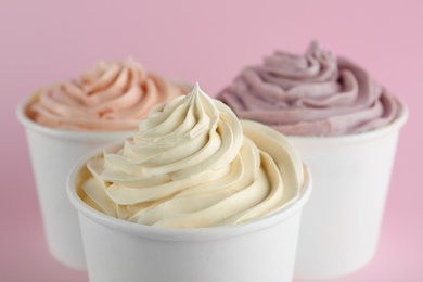 Cups with tasty frozen yogurts on pink background, closeup