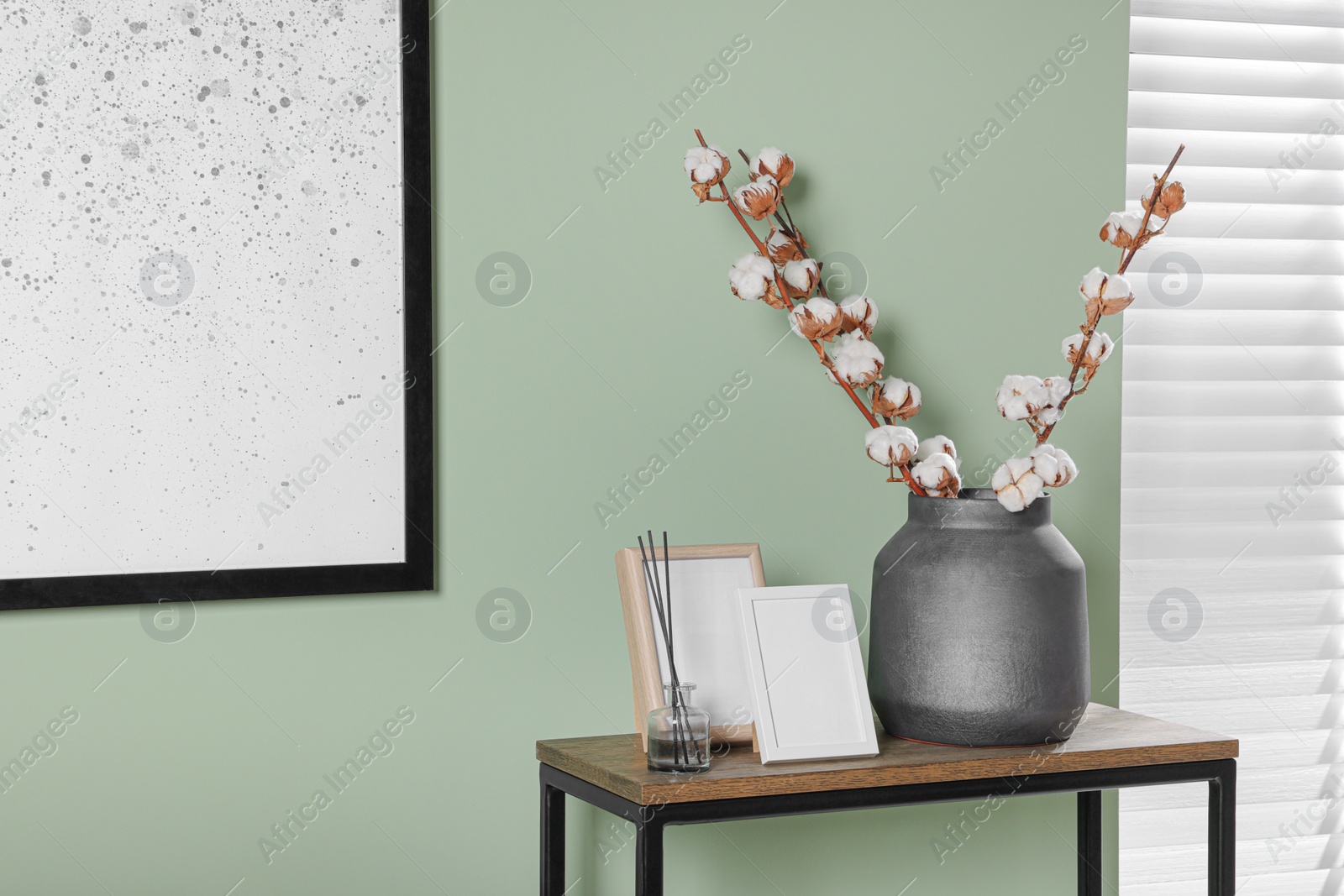 Photo of Branches with white fluffy cotton flowers on console table in cozy room. Interior design