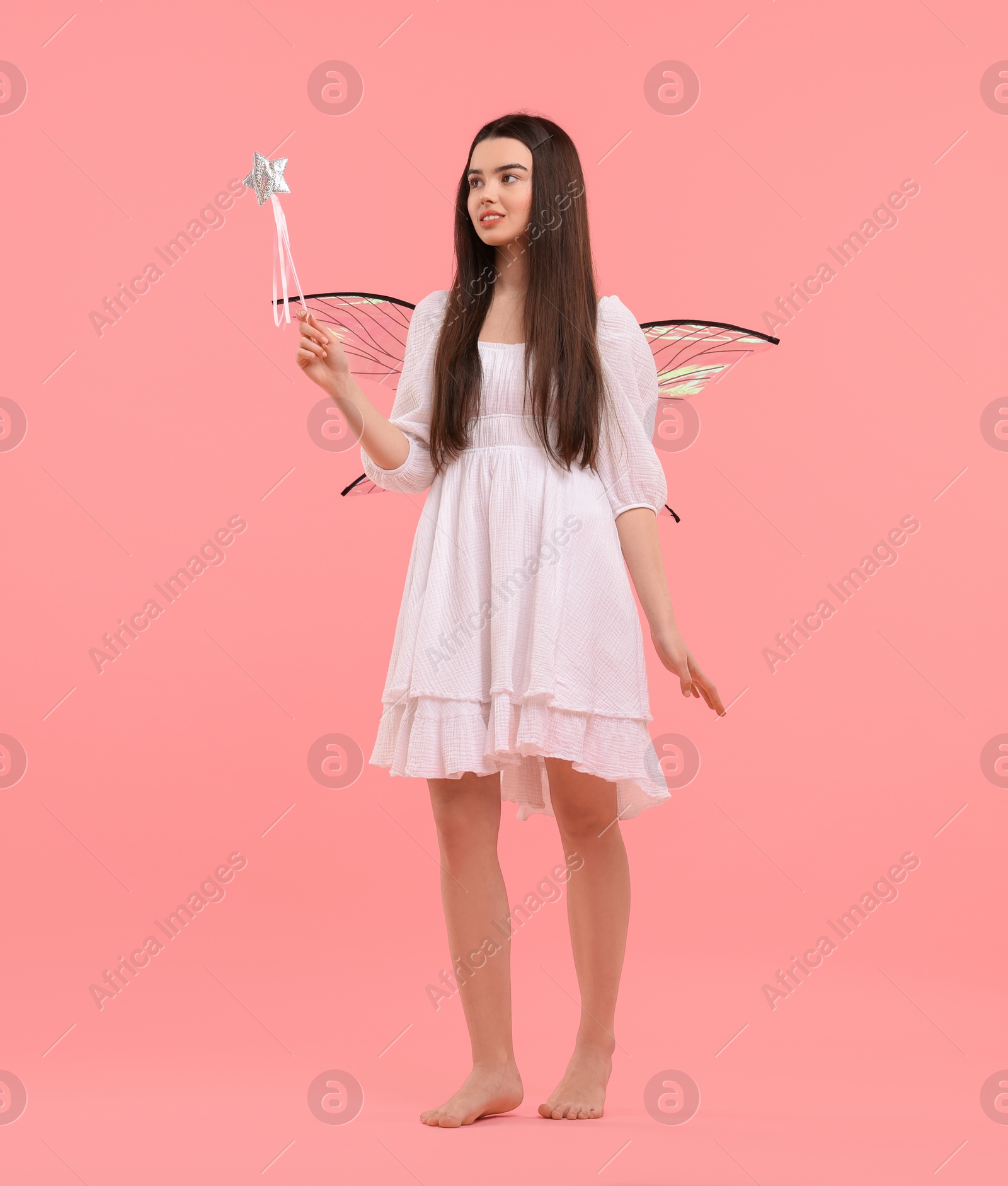 Photo of Beautiful girl in fairy costume with wings and magic wand on pink background, space for text