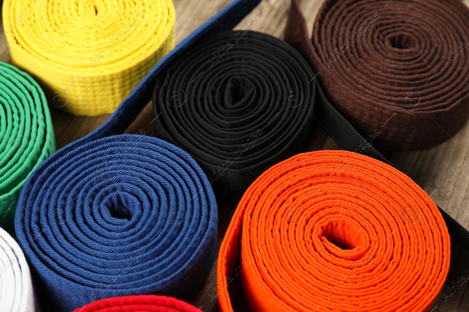Photo of Colorful karate belts, closeup. Martial arts uniform