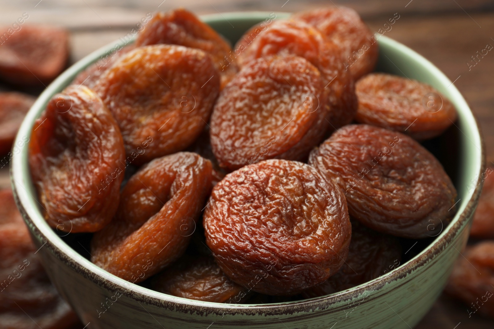 Photo of Bowl of tasty apricots on table, closeup. Dried fruits