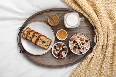 Photo of Tray with tasty breakfast on bed in morning, flat lay
