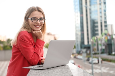 Photo of Beautiful businesswoman with glasses using laptop in city
