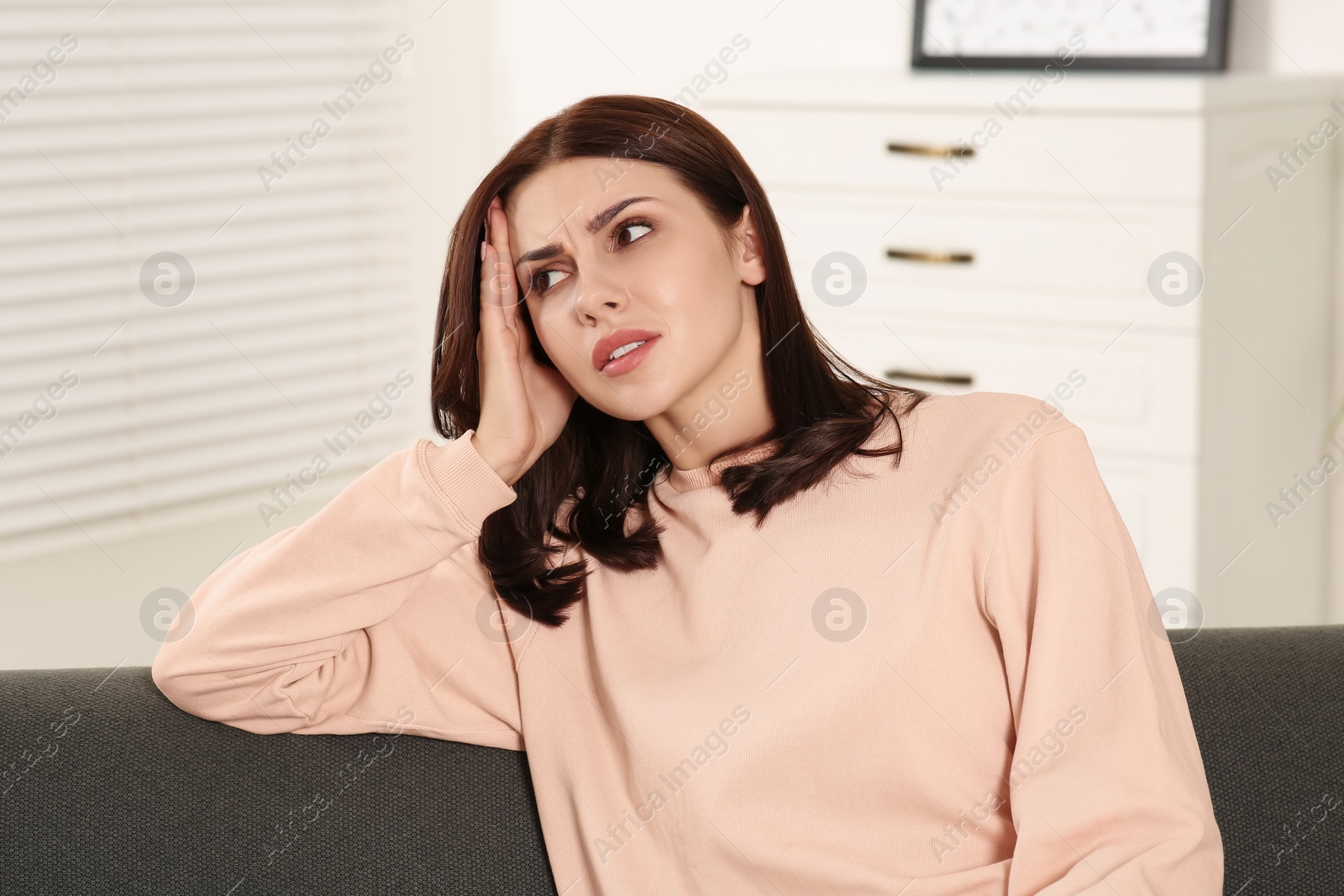 Photo of Young woman suffering from headache indoors. Hormonal disorders