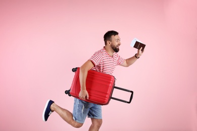 Photo of Man with suitcase and passport running on color background. Vacation travel