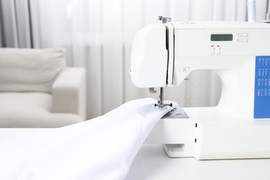 Photo of White sewing machine and fabric indoors, closeup