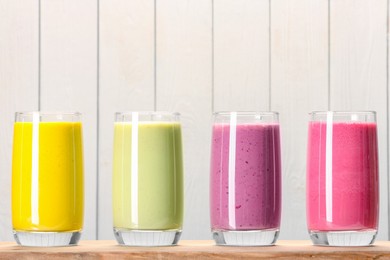 Photo of Board with many different tasty smoothies against white wooden background, space for text