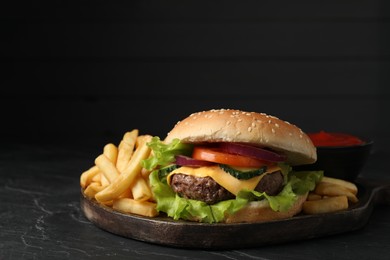 Delicious burger and french fries served on black table
