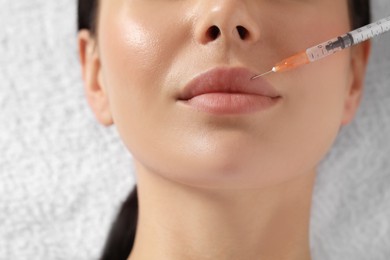Photo of Young woman getting lip injection in clinic, closeup. Cosmetic surgery