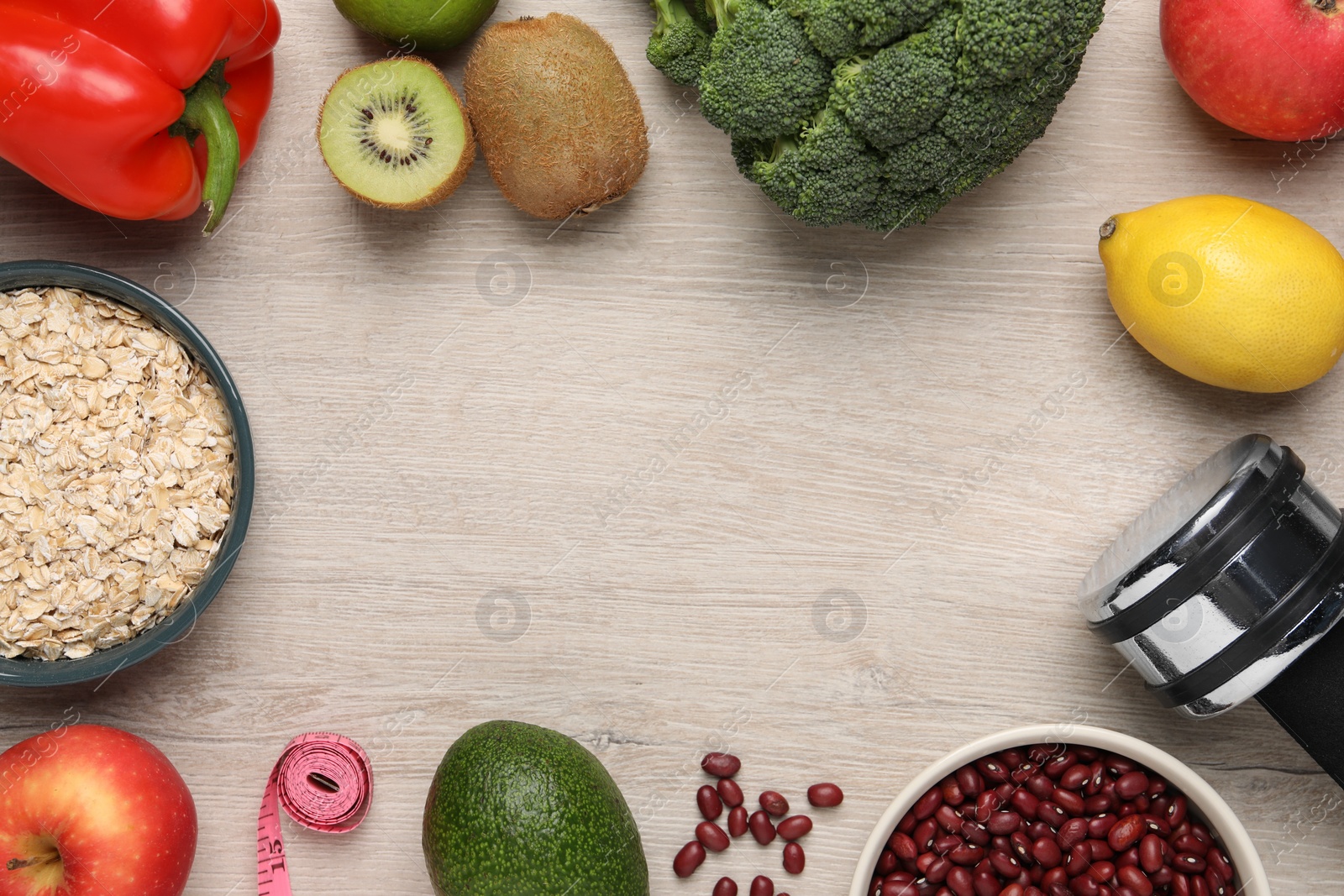 Photo of Healthy diet. Frame of different products, dumbbell and measuring tape on light wooden table, flat lay. Space for text