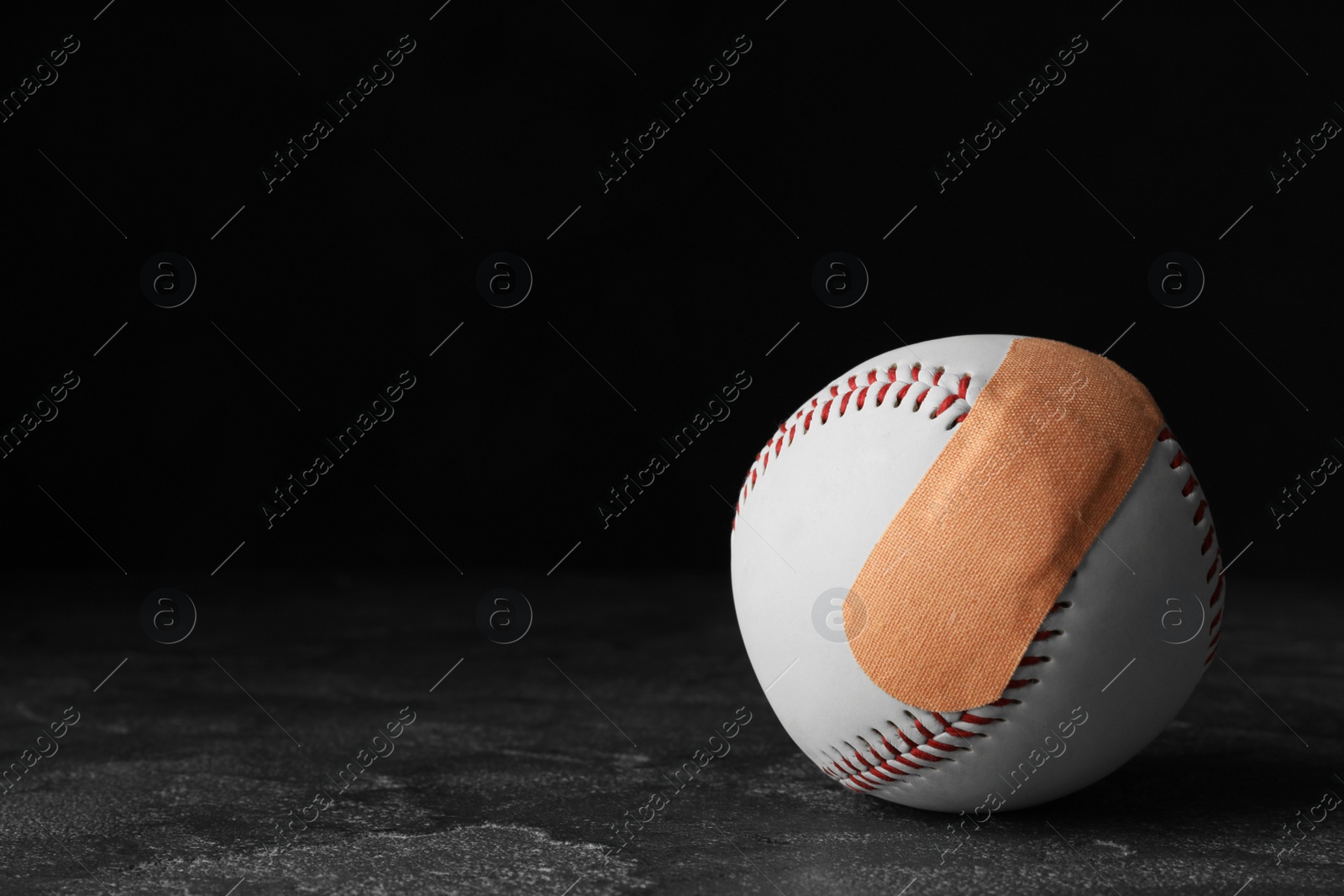 Photo of Ball with sticking plasters on grey stone table, space for text
