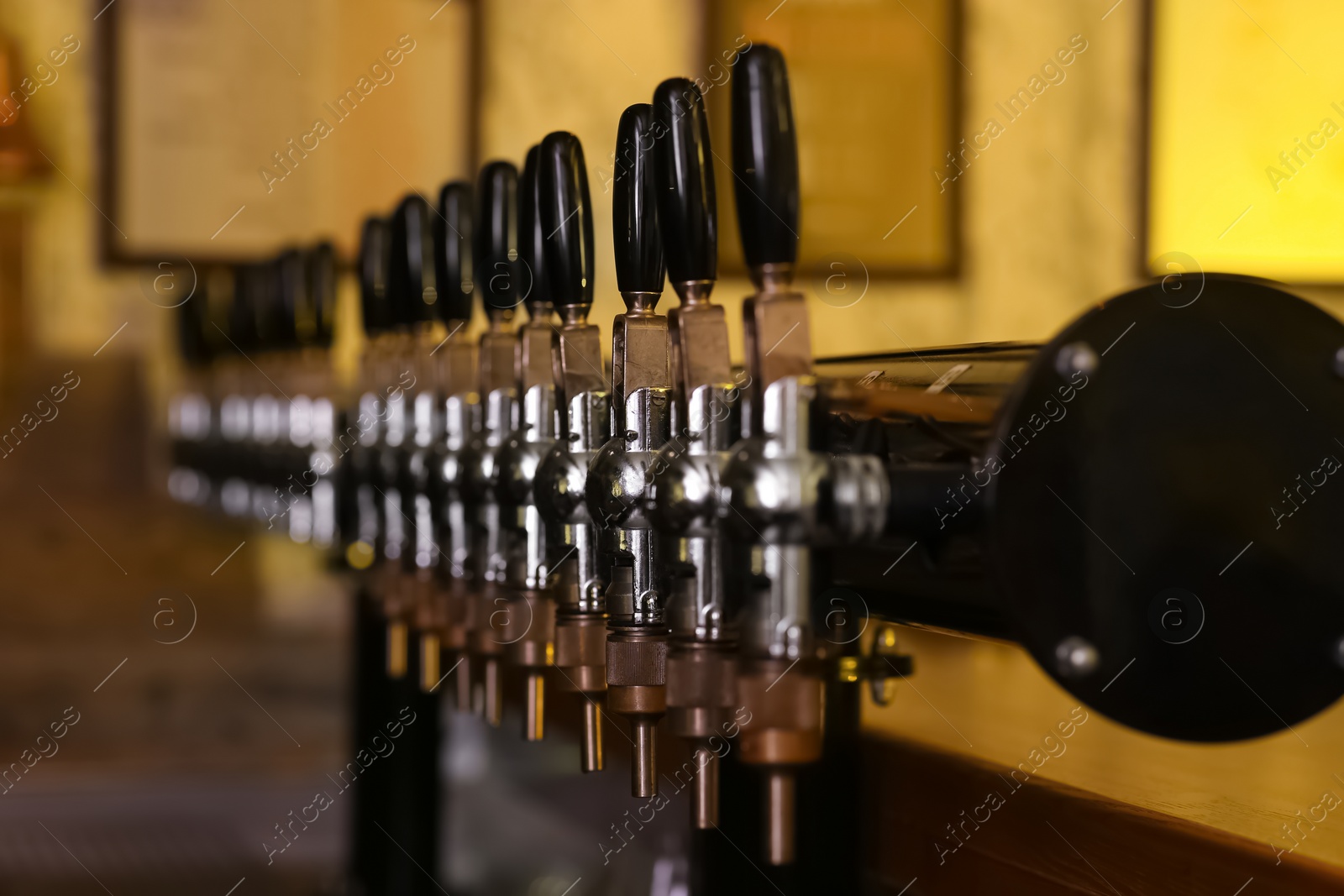 Photo of New modern beer taps in pub, closeup. Professional bar equipment