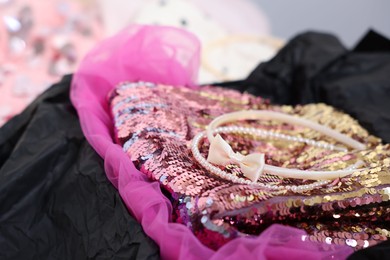 Headbands and stylish pink carnival costume with sequins in black box, closeup