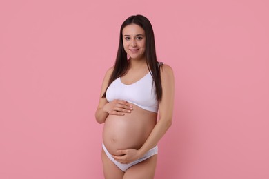 Beautiful pregnant woman in stylish comfortable underwear on pink background