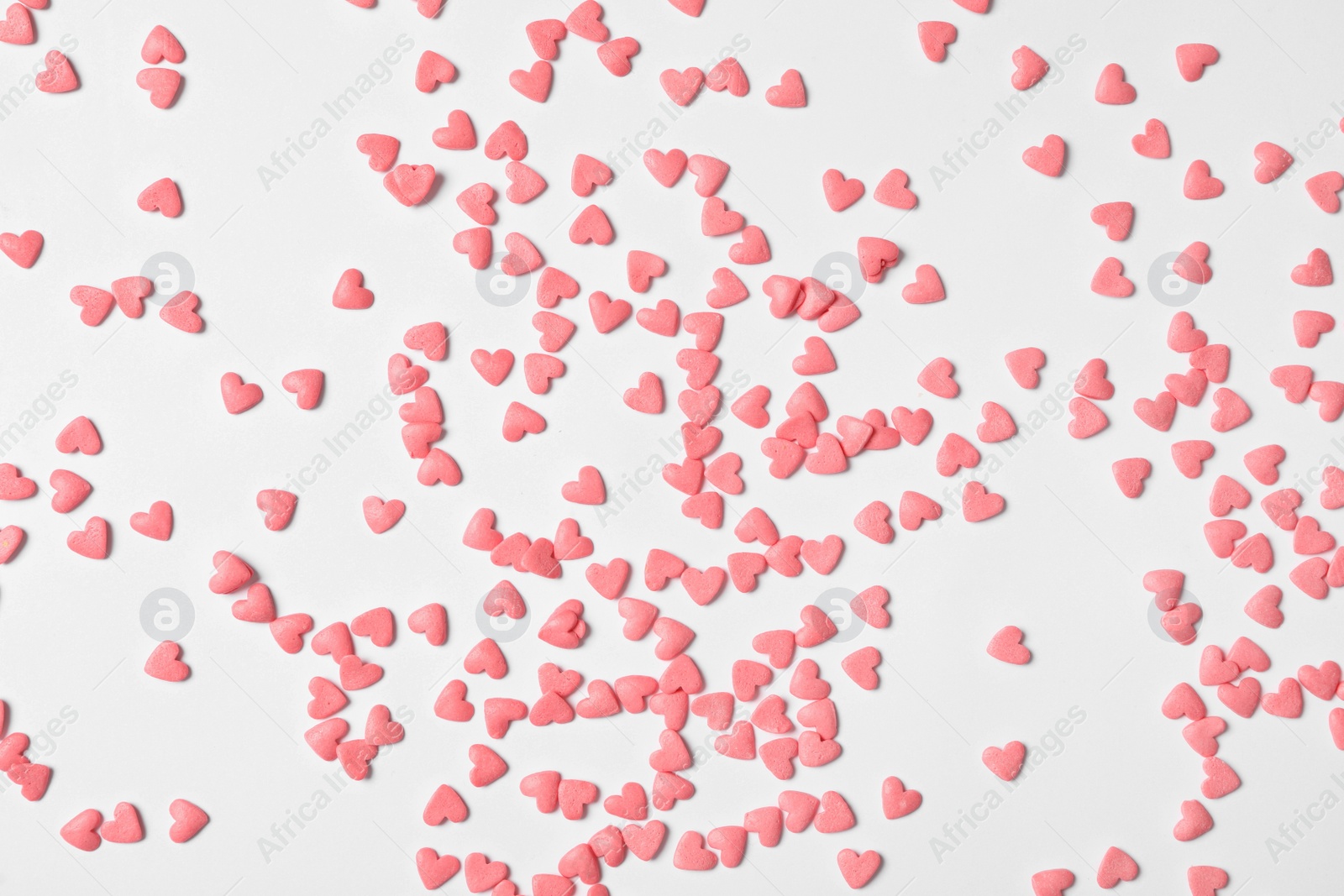 Photo of Pink heart shaped sprinkles on white background, flat lay