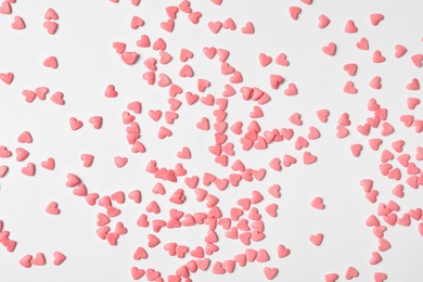 Photo of Pink heart shaped sprinkles on white background, flat lay