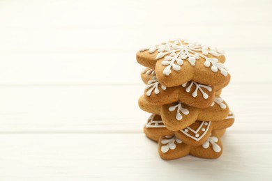 Photo of Stack of tasty Christmas cookies with icing on white wooden table. Space for text