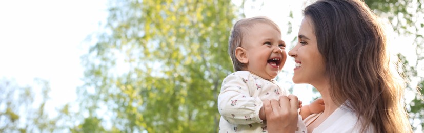 Happy mother with her cute baby in park on sunny day, space for text. Banner design