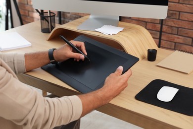 Professional retoucher working on graphic tablet at desk, closeup