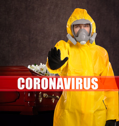 Funeral during coronavirus pandemic. Man in protective suit near casket indoors