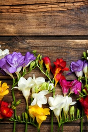 Photo of Beautiful freesia flowers on wooden background