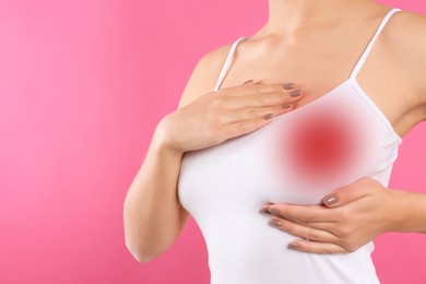 Image of Woman checking her breast on pink background, closeup