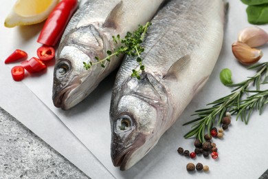 Photo of Sea bass fish and ingredients on grey table, closeup
