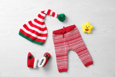 Photo of Set of festive baby clothes and accessories on wooden background, flat lay