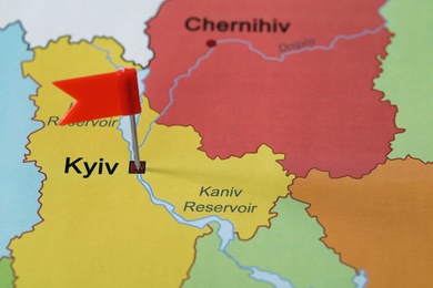 Map of Ukraine with red flag push pin placed on Kyiv, closeup