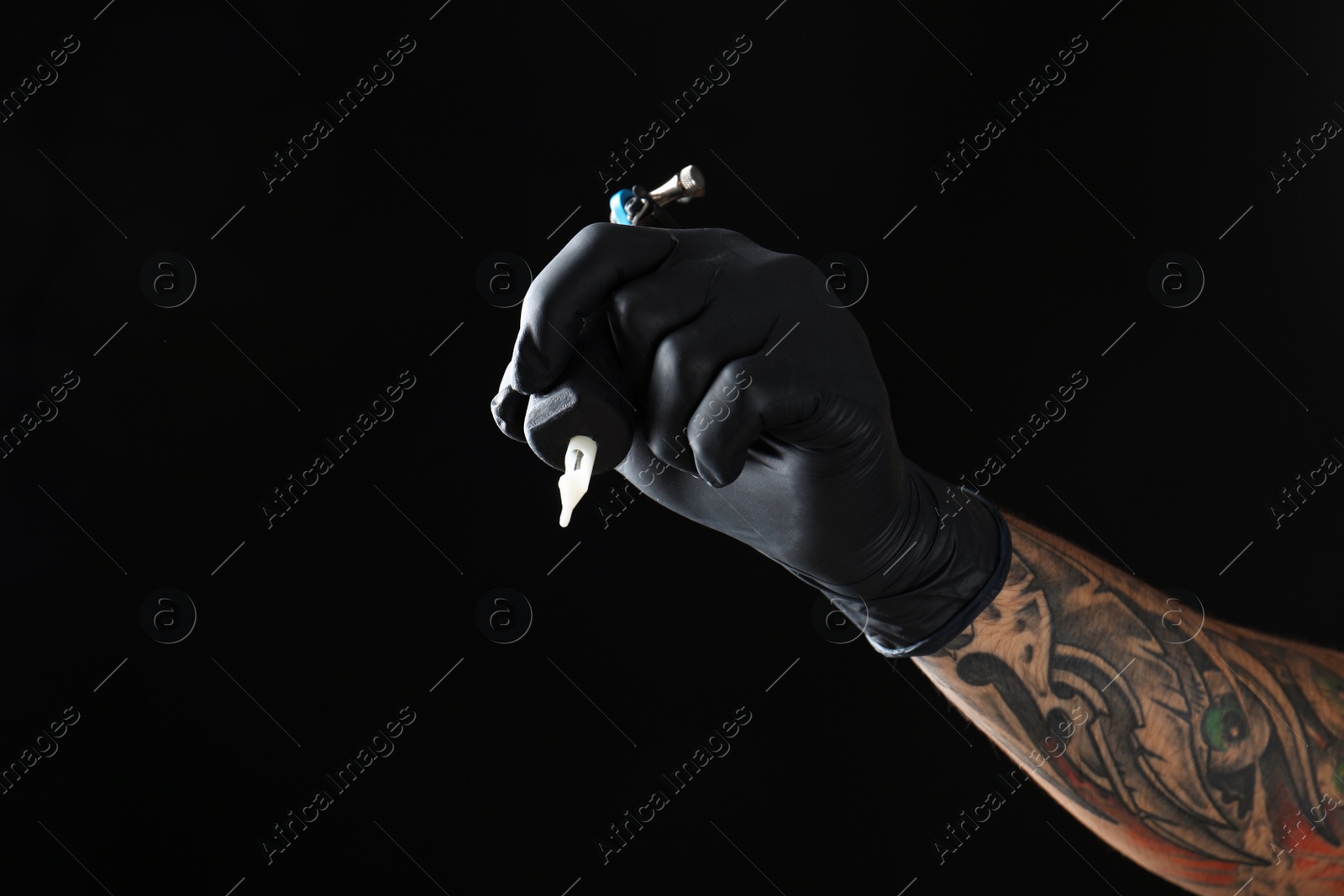 Photo of Professional tattoo artist with machine on black background, closeup. Space for text