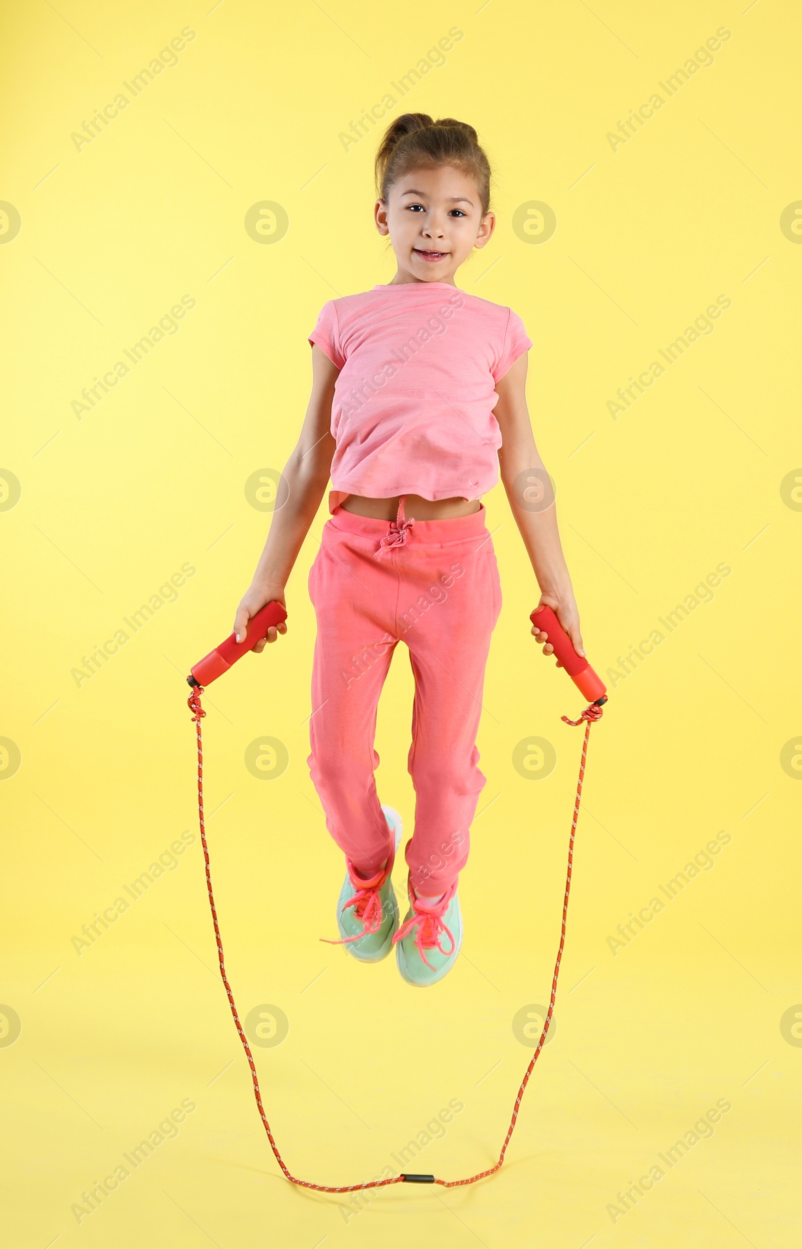 Photo of Full length portrait of girl jumping rope on color background