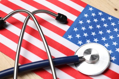 Stethoscope and USA flag on wooden table, closeup. Health care concept