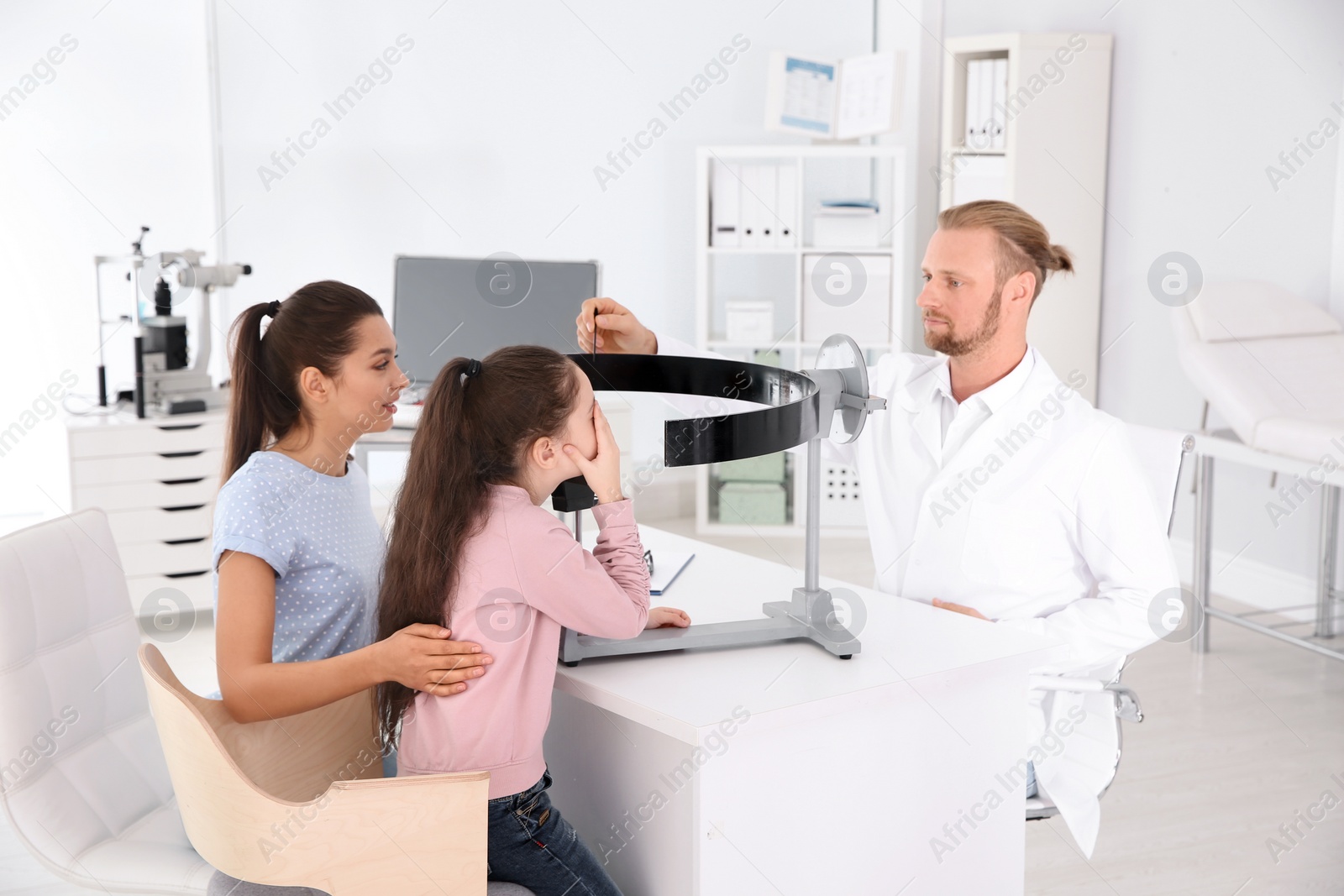 Photo of Children's doctor examining girl's vision at office