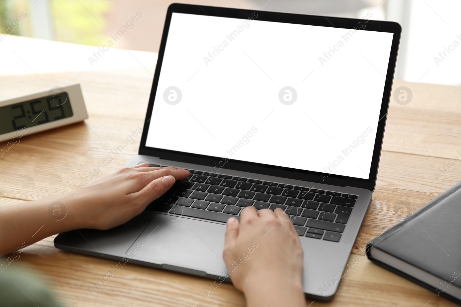 Photo of Woman working with modern laptop at wooden table, closeup. Space for design