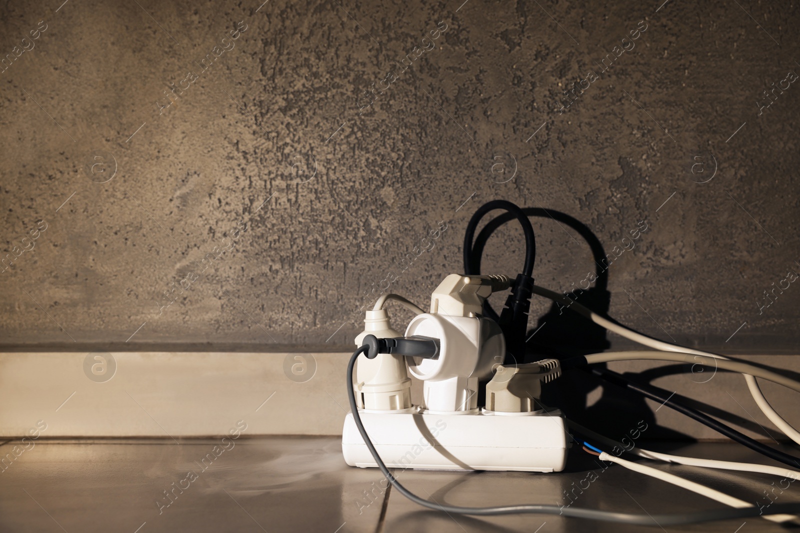 Photo of Many plugs in power strip indoors, space for text. Risk of short circuit
